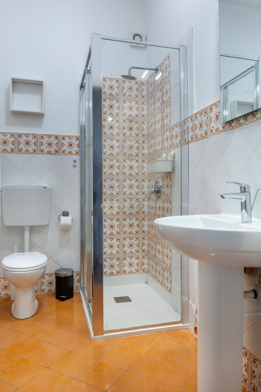 Bagno con doccia in cristallo e maioliche decorate color terracotta